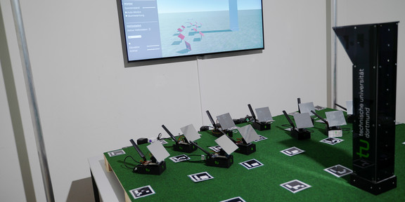 Small-scaled build of a solar energy plant and a screen with the digital twin in the background