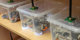Plastic boxes in a shelf with mini-computers on them
