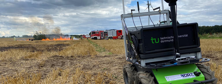 A robotic platform on a field with fire in the background